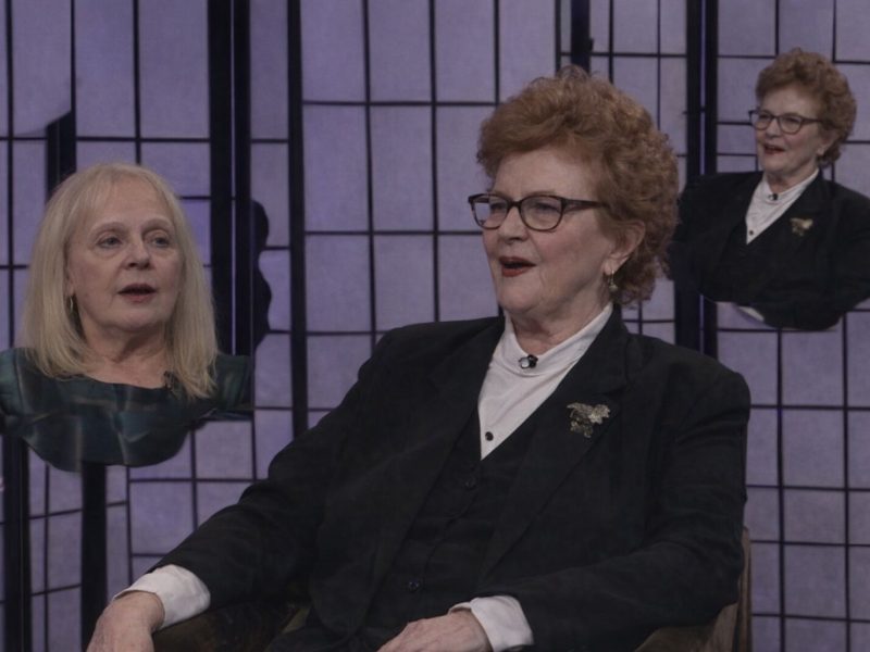 Skådespelare med peruk och tidstypisk frisyr på en teaterscen.